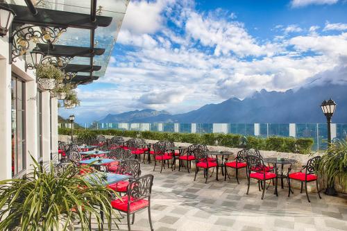 a patio with tables and chairs with mountains in the background at Silk Path Grand Sapa Resort & Spa in Sa Pa