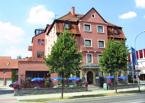 a pink building with blue umbrellas on a street at Hotel Rothenburger Hof in Rothenburg ob der Tauber