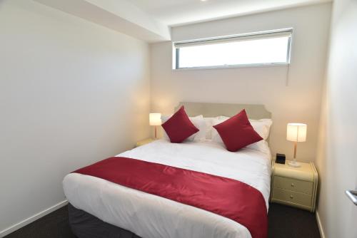 a bedroom with a large bed with red pillows at Bealey Plaza Motel in Christchurch