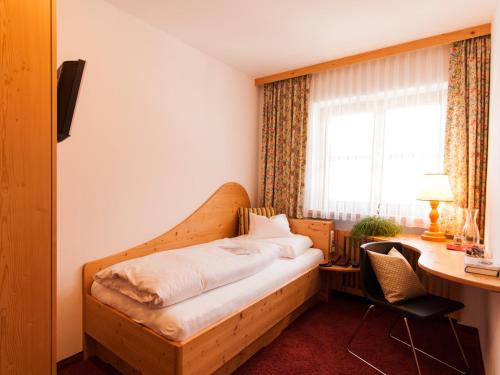 a bed in a room with a desk and a bed sidx sidx sidx at Pension Kilian in Lech am Arlberg