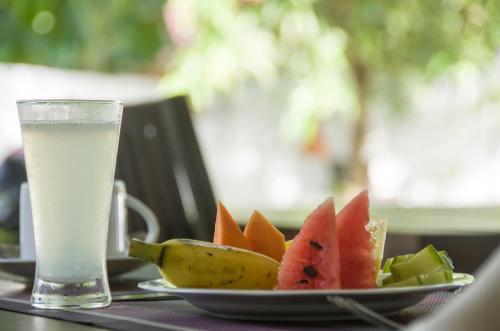a plate of fruit and a glass of milk on a table at Andorra Tourist Resort Anuradhapura in Anuradhapura