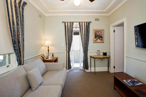 a living room with a couch and a window at The Hughenden Boutique Hotel in Sydney