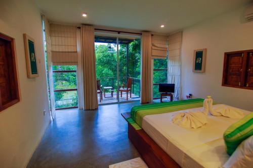 a bedroom with a bed and a view of a balcony at Eliyanth Udawalawe in Udawalawe