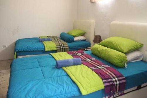 two beds in a room with green and blue at Gedul Homestay in Canggu