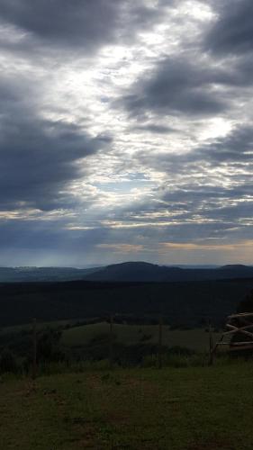 a cloudy sky over a field with a fence at Dargle Forest Lodge in Dargle