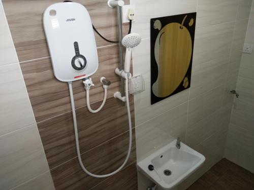 a shower with a hair dryer and a sink in a bathroom at Harum Manis Country House in Kangar