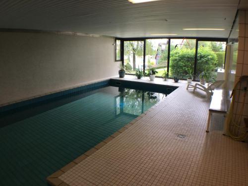 a swimming pool with a green tiled floor and windows at schwarzwald-apartment in Schönwald