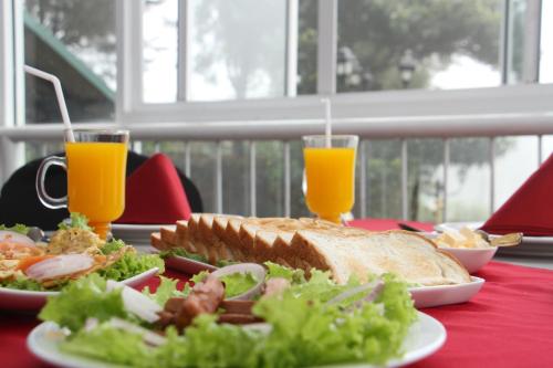 a table with a plate of food and two glasses of orange juice at Misty Paradise of Lake Gregory in Nuwara Eliya