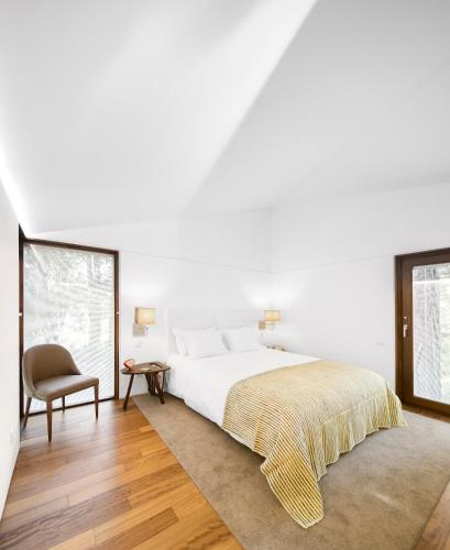 a bedroom with a large bed and a chair at Pedras Salgadas Spa & Nature Park in Pedras Salgadas