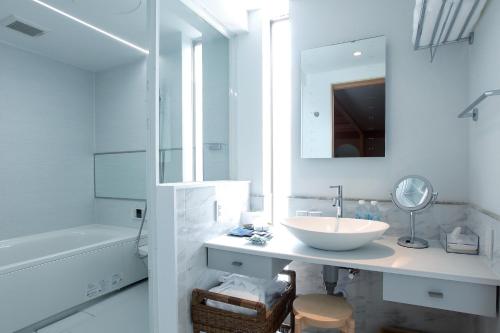 a white bathroom with a sink and a mirror at Luxury Condo Shikine An Gion Shirakawa in Kyoto