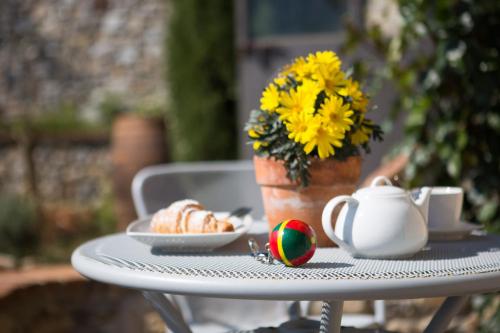 a table with a vase of flowers and a plate of food at Agriturismo Borghetto Il Montino in Rapolano Terme