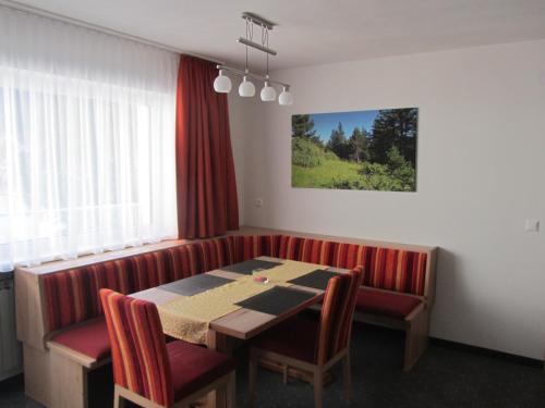 a dining room with a table and red chairs at Appartements Kroner in Nauders