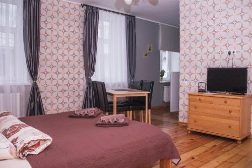 a bedroom with a bed and a desk and a television at Ventspils Centra Apartamenti in Ventspils