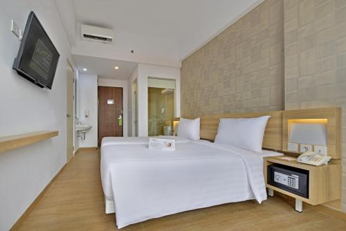 a bedroom with a large white bed and a television at Whiz Prime Hotel Basuki Rahmat Malang in Malang