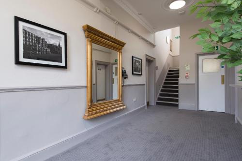 a hallway with a mirror on the wall and stairs at Owl, Hambleton by Marston's Inns in Selby