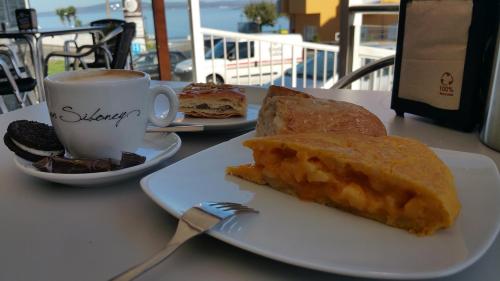 a table with two plates of food and a cup of coffee at Hotel Crisol de las Rías in Miño