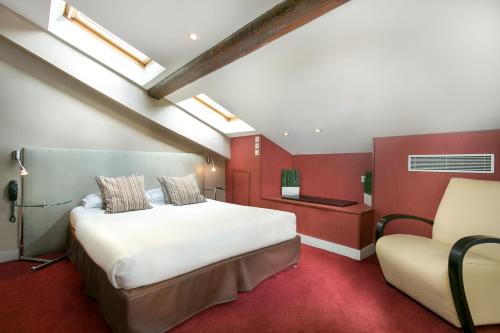 a hotel room with a bed and a chair at Porte de Versailles Hotel in Paris