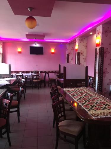 a dining room with tables and chairs and purple lights at Pensiunea Cascada in Comăneşti