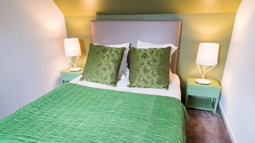 um quarto com uma cama com lençóis e almofadas verdes em Cottage "Les ETANGS" à quelques pas du Lac de la forêt d'Orient - Les Cottages du Belvédère em Mesnil-Saint-Père