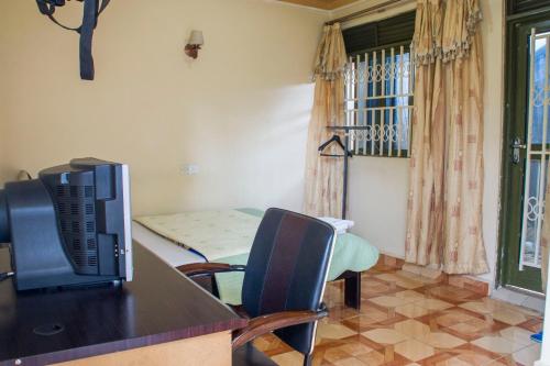 a room with a table with a tv and chairs at Rays Hotel in Mbarara