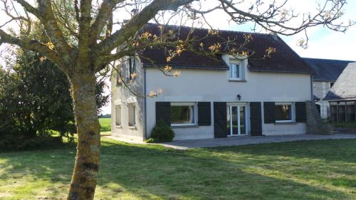 une maison blanche avec un arbre devant dans l'établissement Gite le Courbat, à Le Liège