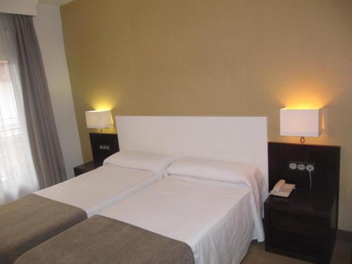 a hotel room with two beds and two lamps at Don Juan in Granada