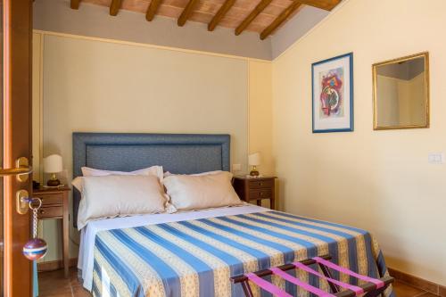 a bedroom with a bed with a blue and white striped blanket at Agriturismo Borghetto Il Montino in Rapolano Terme