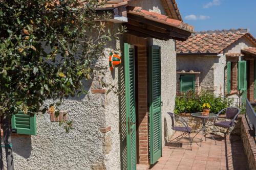 a house with green shutters and a table and chairs at Agriturismo Borghetto Il Montino in Rapolano Terme