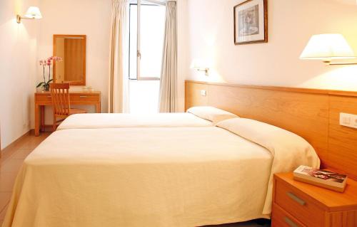 ポルト・ダ・ポリェンサにあるApartamentos Miramar 2のベッド2台とデスクが備わるホテルルームです。