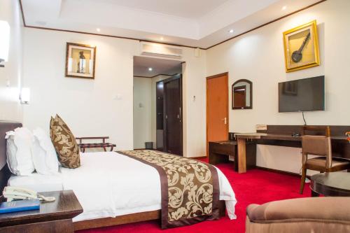 ein Hotelzimmer mit einem Bett und einem Schreibtisch in der Unterkunft Lake View Resort Hotel in Mbarara
