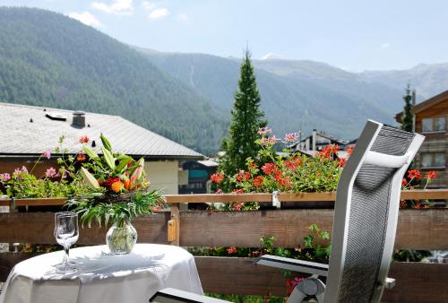 una mesa con un jarrón de flores y una copa de vino en Hotel Ambassador Zermatt, en Zermatt