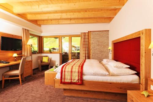 a bedroom with a bed and a desk in a room at Hotel Barbarahof Saalbach in Saalbach Hinterglemm