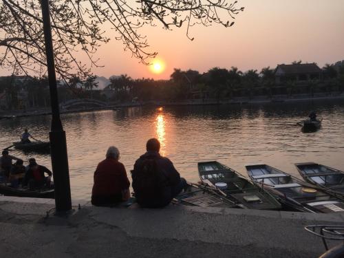 two people sitting on the edge of a lake watching the sunset at Tam Coc Boutique Garden in Ninh Binh