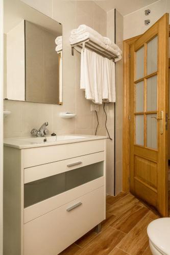 a bathroom with a sink and a mirror and a toilet at Viviendas de Uso Turístico in Porto do Son