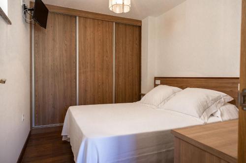 ポルト・ド・ソンにあるViviendas de Uso Turísticoの白いベッドと木製の壁が備わるベッドルーム1室が備わります。