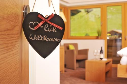 un signo en forma de corazón colgando de una puerta en Hotel Barbarahof Saalbach en Saalbach Hinterglemm