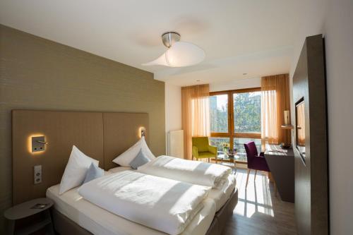 a bedroom with a large white bed and a desk at Hotel Knoblauch in Friedrichshafen