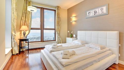 a large white bed in a room with a large window at Dom & House - Apartamenty Sea Towers in Gdynia