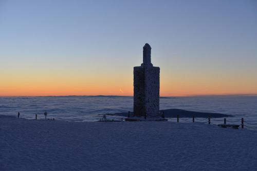 a tower in the snow with the sunset in the background at Hotel Belweder - przy hotelu Golebiewski in Karpacz