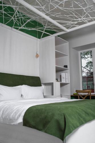 a bedroom with a bed with a green blanket on it at City Hotel Bortoli by Ribas in Odesa