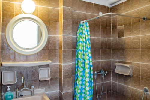 a bathroom with a shower with a sink and a mirror at Hotel Tarsanas in Pythagoreio