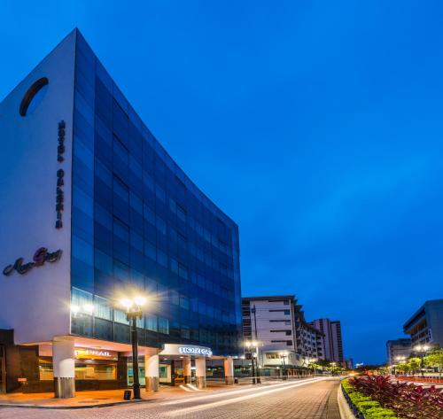 a large glass building on a city street at night at GH Galeria Hotel in Guayaquil