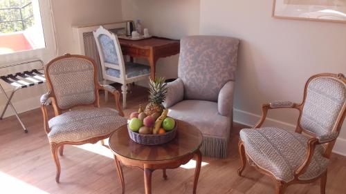 a living room with a chair and a table with a bowl of fruit at Hôtel Chantaco Golf & Wellness in Saint-Jean-de-Luz