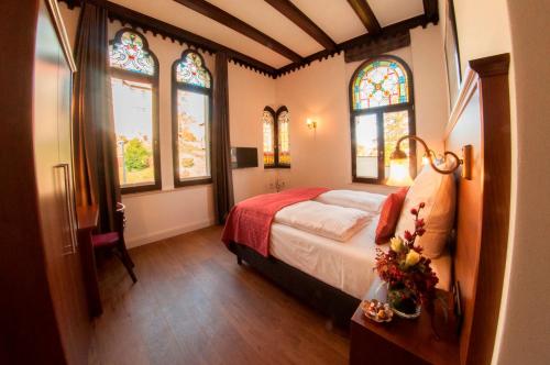 a bedroom with a bed and stained glass windows at Pension VILLA KLEINE WARTBURG in Eisenach