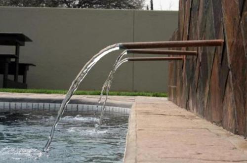 a stream of water pouring into a swimming pool at Hadassa Guest House in Otjiwarongo