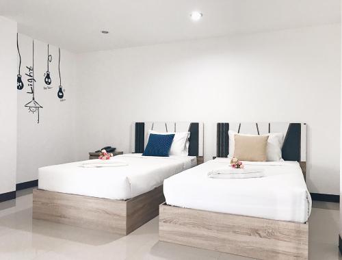 two beds in a room with white walls at Rinn Boutique House in Chiang Mai