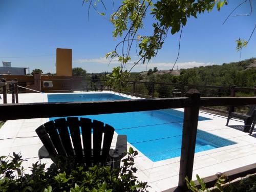 a swimming pool with a black chair next to a fence at La Osadia Cabañas y Suites Solo Adultos in Mina Clavero