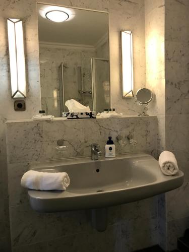 a bathroom with a sink and a mirror and towels at Hotel De Insulåner in Langeoog