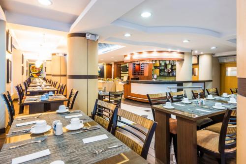 a restaurant with wooden tables and chairs and a bar at GH Galeria Hotel in Guayaquil