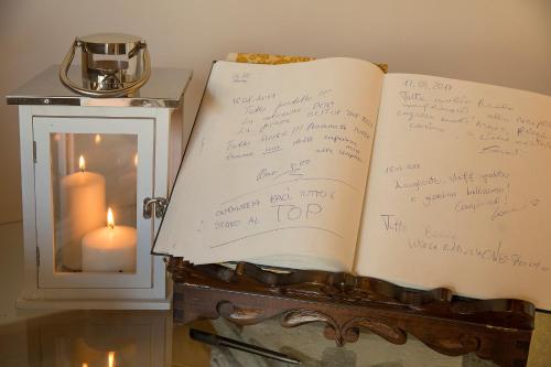 an open book with writing on it next to a candle at Relais dell'Olmo in Perugia